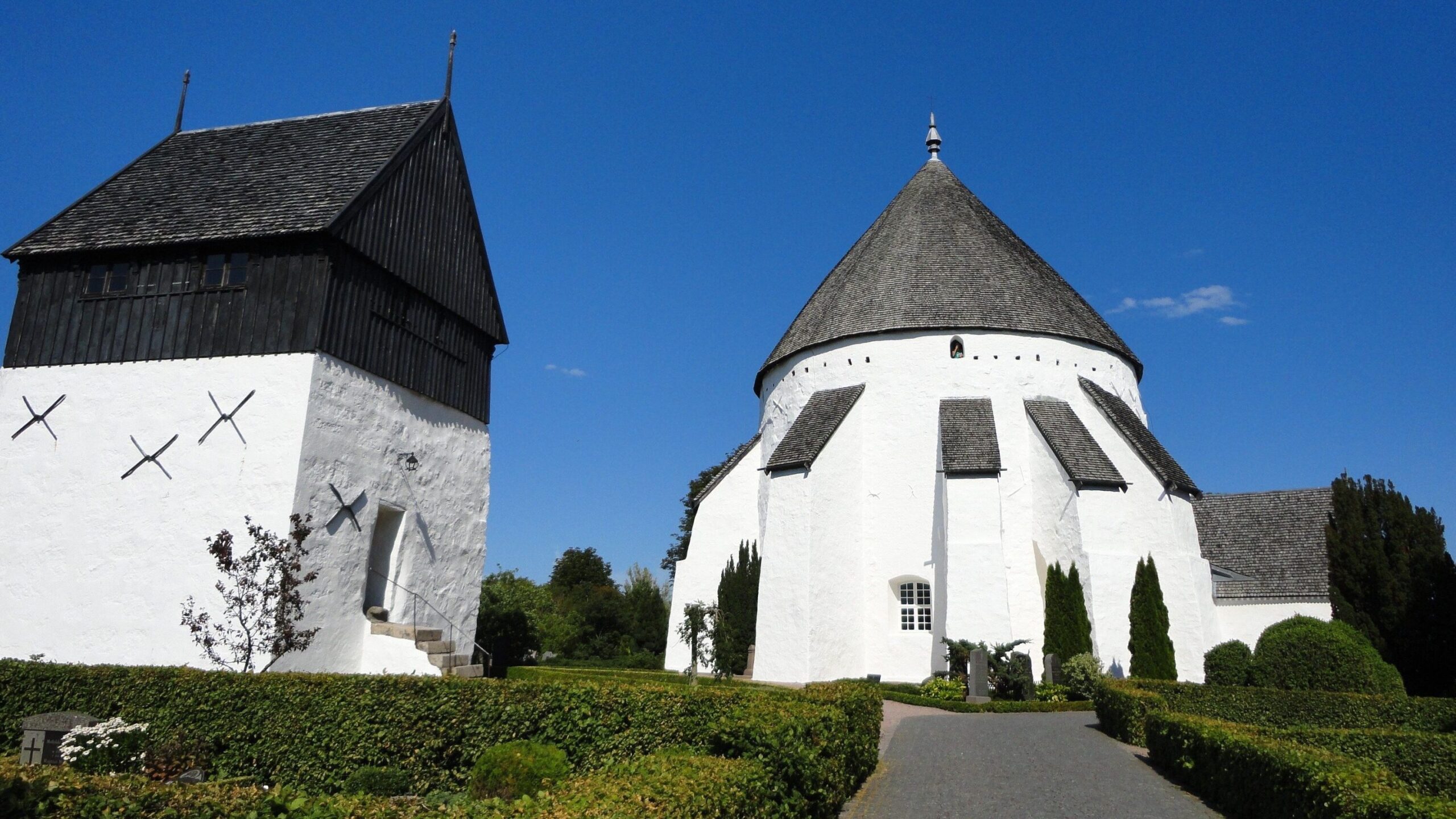 Weiße Rundkirche von Østerlars und Glockenturm mit schwarzem Giebel