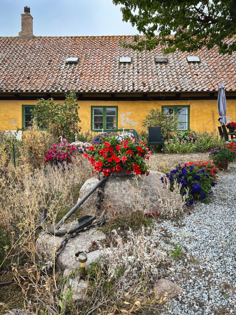 Gelbes Haus mit Ziegeldach und Blumen im Vorgarten