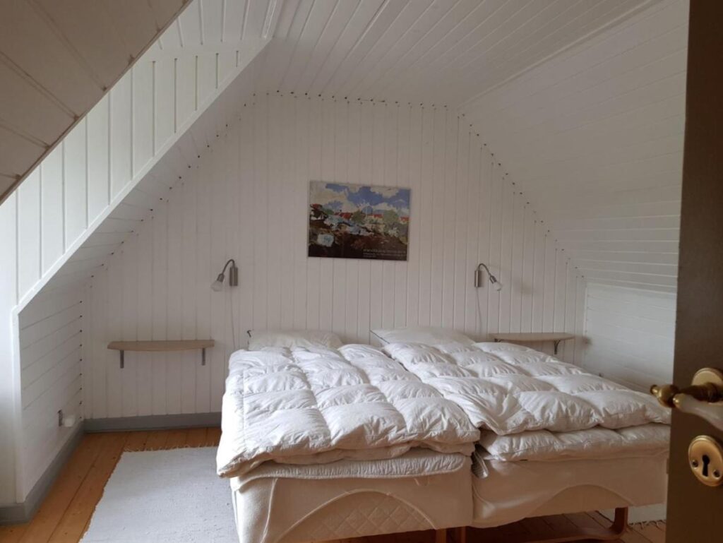 Schlafzimmer im Dachgeschoss mit weißer Holzverkleidung und zwei zusammengeschobenen Betten