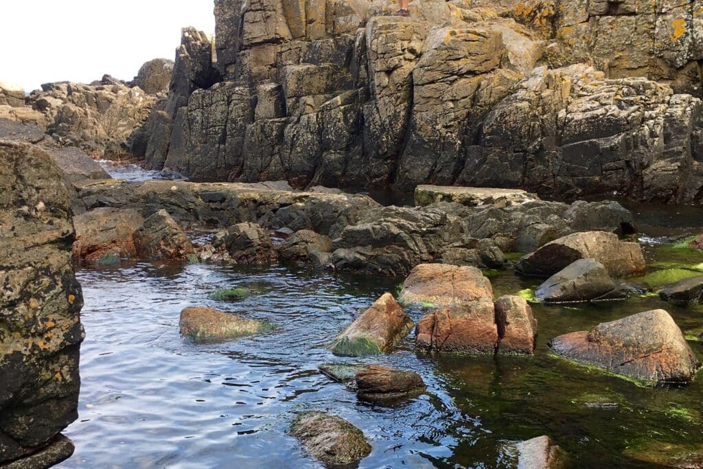 Granitfelsen und Findlinge im flachen Wasser am Fuß der Helligdomsklipperne