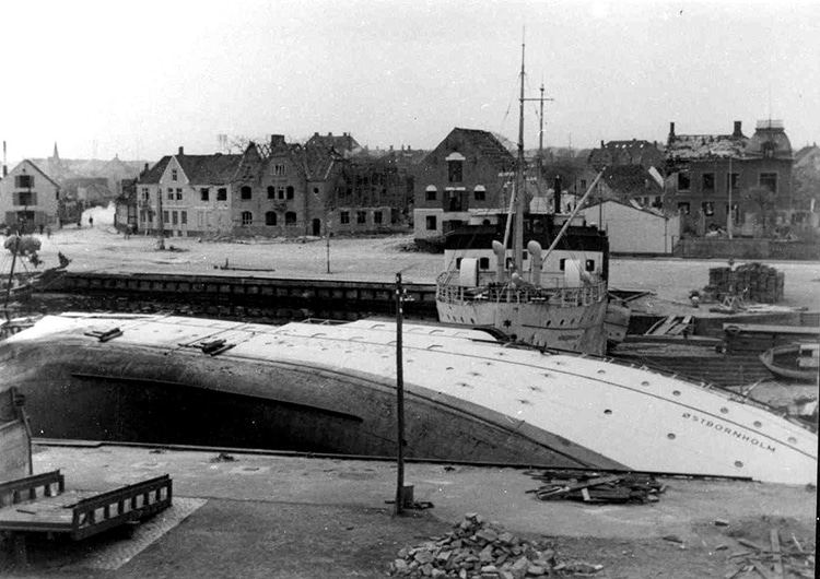 Zerstörter Hafen von Nexø 1945: seitlich umgekipptes Schiff Østbornholm und Häuser ohne Dächer, Archivfoto