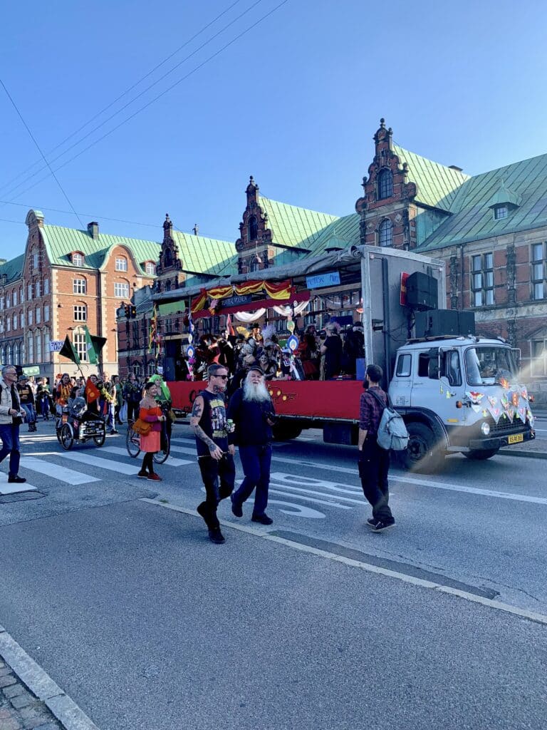 Umzug mit geschmücktem Lkw vor einem historischen Gebäude mit grünem Dach