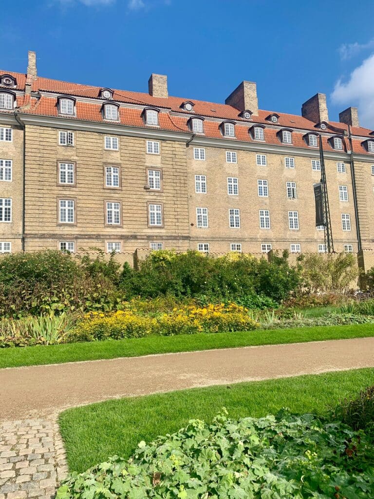 Großes Gebäude mit rotem Dach hinter einem Blumenbeet im Park