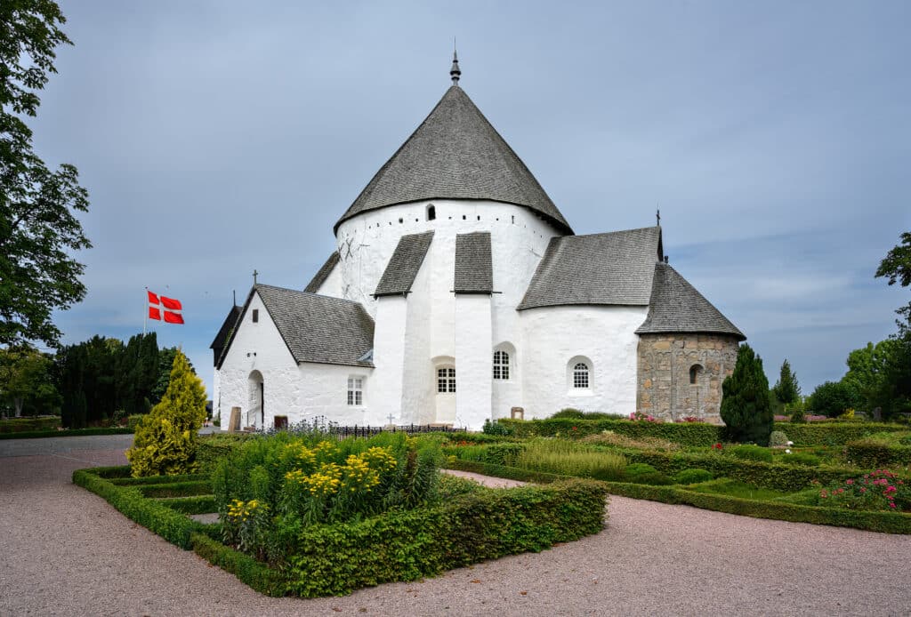 Rundkirche von Østerlars mit dänischer Flagge und Garten mit Hecken