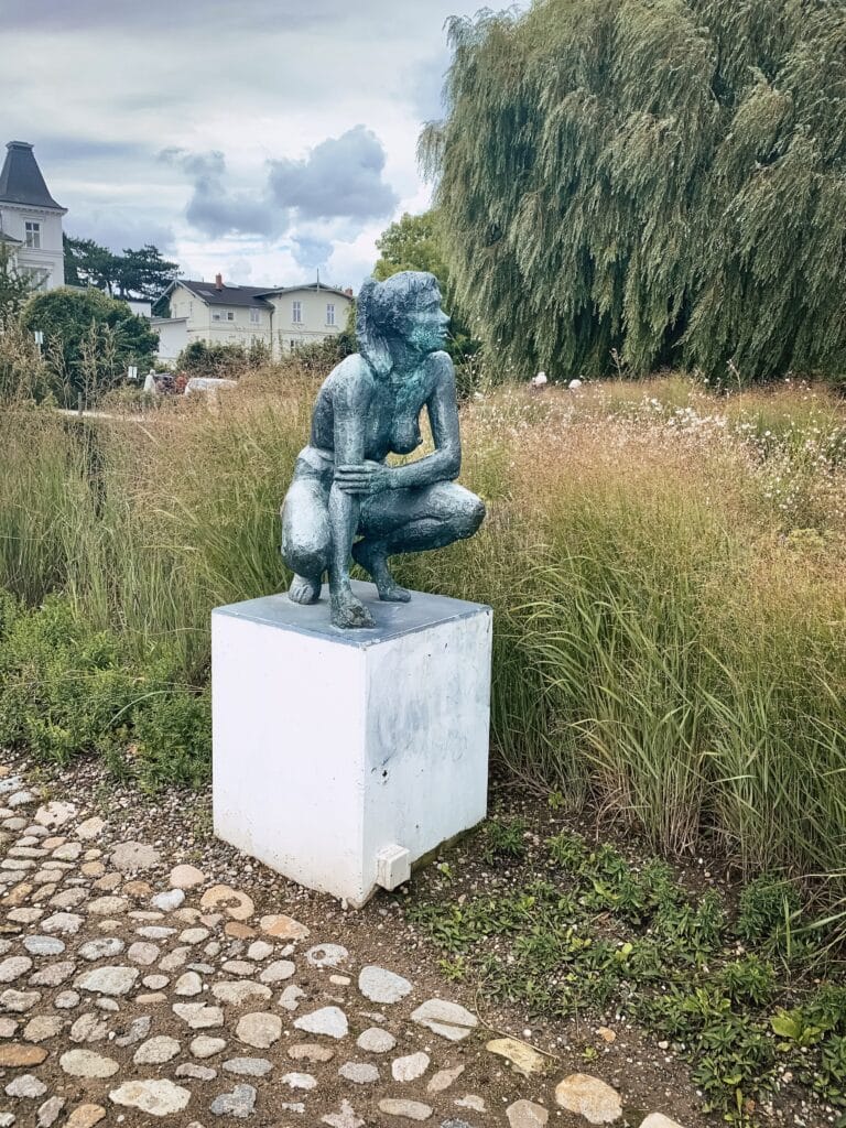 Skulptur auf einem Sockel an einem gepflasterten Weg in Stralsund
