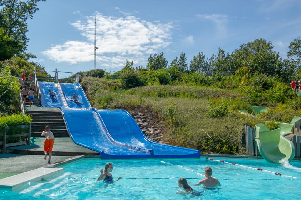 Blaue Wasserrutschen und ein Becken mit badenden Kindern im Joboland