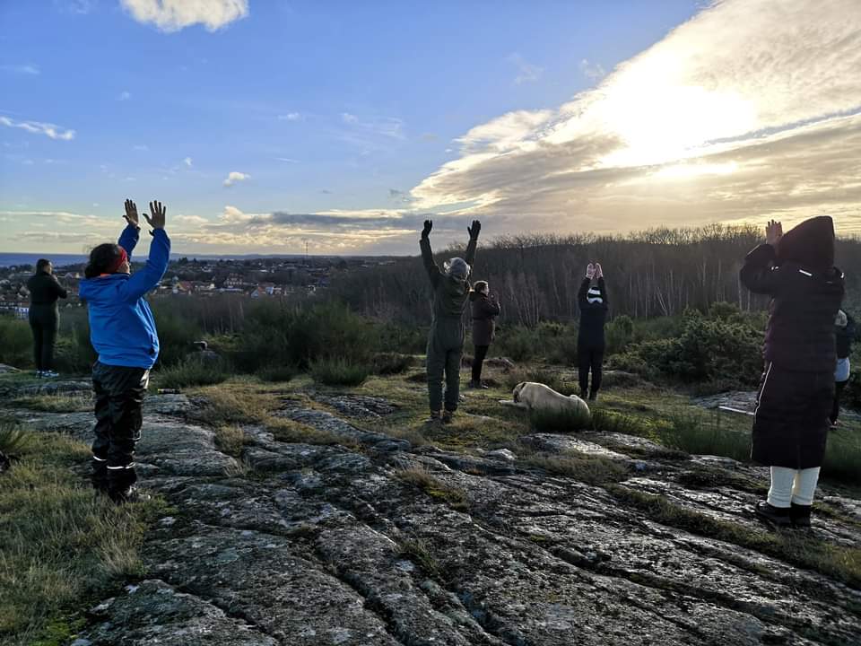 Gruppe beim Yoga mit erhobenen Armen auf den Felsen von Hammerknuden