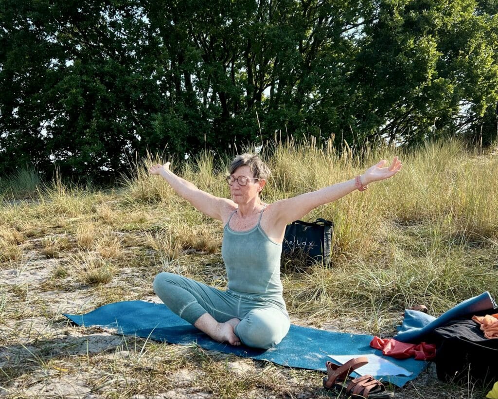Yogalehrerin auf der Matte zwischen Strandgräsern am Melsted Strand