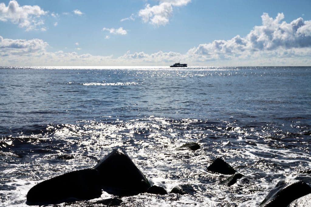 Findlinge im Meer vor der Küste von Jasmund, in der Ferne ein Schiff