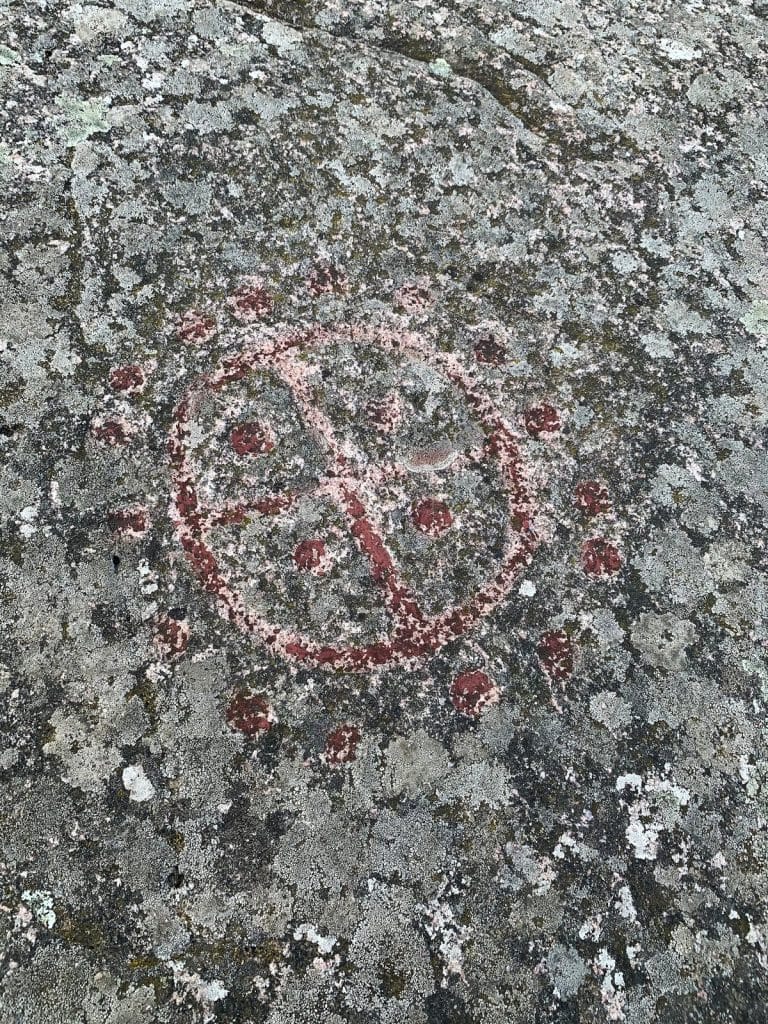 Felsritzung aus der Bronzezeit in Madsebakke: rot ausgemaltes Rad mit Kreuz auf Granit