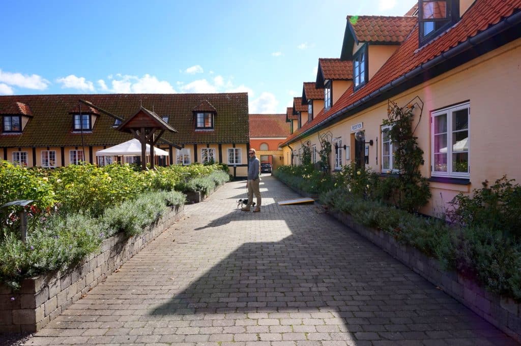 Gepflasterter Hof mit niedrigen Fachwerkhäusern und Blumenbeeten in Svaneke